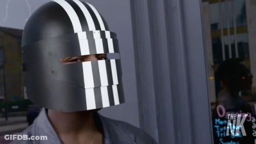 A Person Wearing A Black Helmet With White Stripes On It Stands In Front Of A Sign That Says The Nk GIF