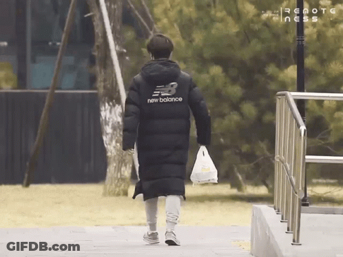 A Person Wearing A Black New Balance Jacket Is Walking Down A Sidewalk GIF