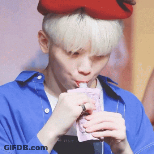 A Person Wearing A Blue Shirt And A Red Hat Drinking From A Bag GIF