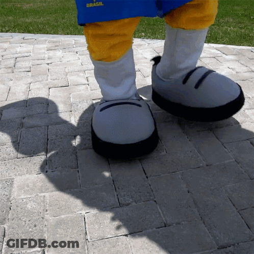 A Person Wearing A Blue Shirt That Says Brasil Is Walking On A Brick Sidewalk GIF