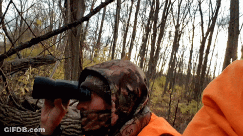 A Person Wearing A Camo Hooded Jacket Looking Through Binoculars GIF