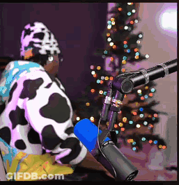 A Person Wearing A Cow Costume Is Sitting In Front Of A Microphone . GIF