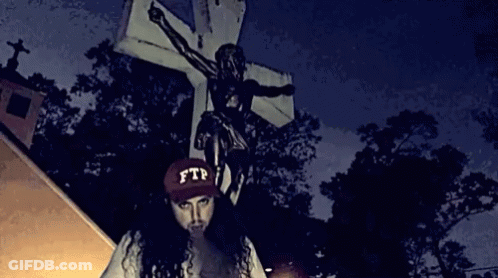 A Person Wearing A Ftp Hat Stands In Front Of A Cross GIF