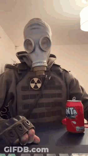 A Person Wearing A Gas Mask Holds A Can Of Fanta GIF