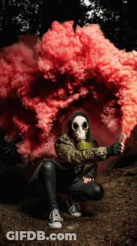 A Person Wearing A Gas Mask Is Holding A Smoke Bomb GIF