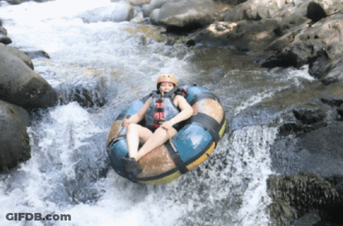 A Person Wearing A Helmet Is Floating Down A River On A Tube GIF