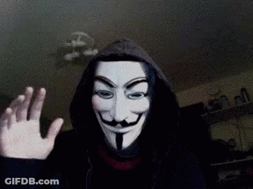A Person Wearing A Hooded Jacket And A Anonymous Mask Is Waving GIF