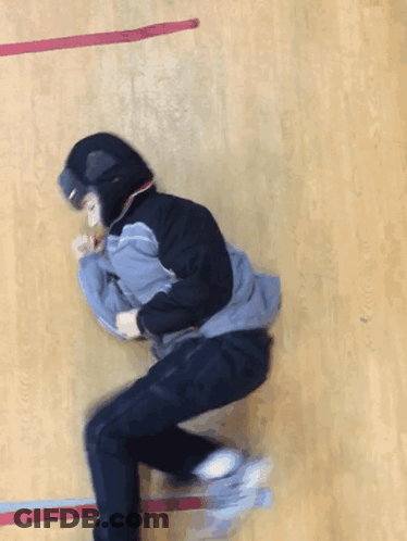 A Person Wearing A Hooded Jacket And Goggles Is Laying On A Wooden Floor GIF