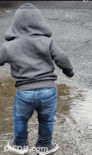 A Person Wearing A Hoodie And Jeans Standing In A Puddle Of Water GIF