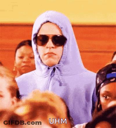 A Person Wearing A Hoodie And Sunglasses Is Standing In A Crowd Of People . GIF