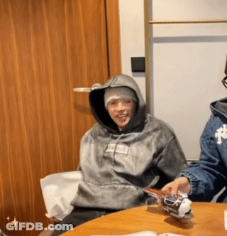 A Person Wearing A Hoodie That Says Supreme On It Sits At A Table GIF