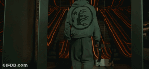 A Person Wearing A Hoodie With A Tree On The Back Walks Down An Escalator GIF
