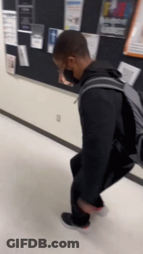 A Person Wearing A Mask And A Backpack Is Walking Down A Hallway GIF