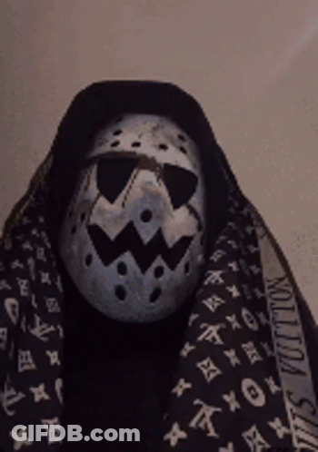 A Person Wearing A Mask And A Louis Vuitton Scarf Around Their Neck GIF