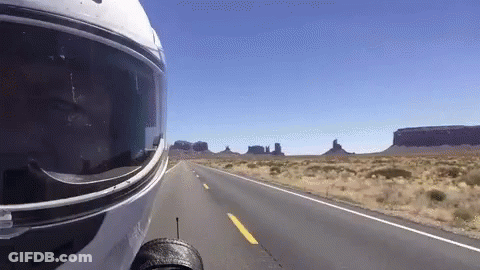 A Person Wearing A Motorcycle Helmet Is Driving Down A Desert Road GIF
