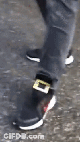 A Person Wearing A Pair Of Black And White Shoes With A Yellow Buckle On The Side . GIF