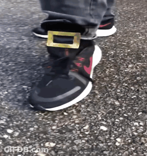 A Person Wearing A Pair Of Nike Shoes With A Gold Buckle GIF
