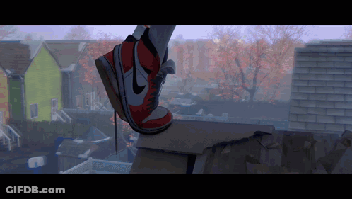 A Person Wearing A Pair Of Red And White Nike Shoes Is Standing On A Ledge GIF