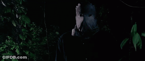 A Person Wearing A Paper Bag On Their Face Is Standing In The Dark . GIF