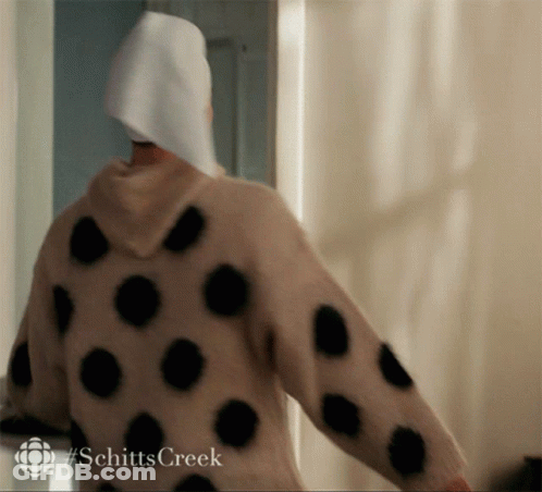 A Person Wearing A Polka Dot Sweater With #Schittscreek On The Bottom GIF