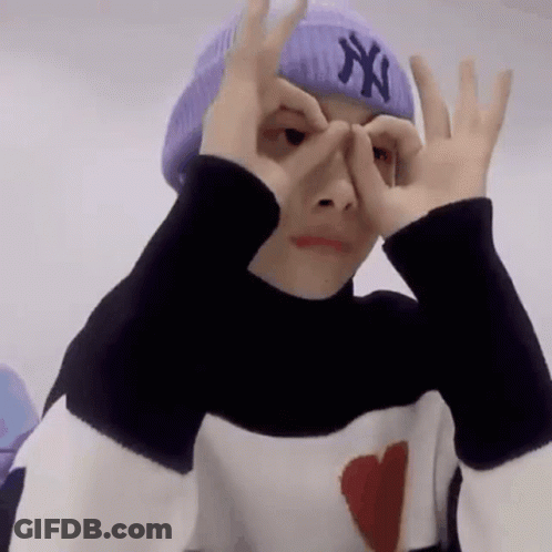 A Person Wearing A Purple Hat And A Black And White Sweater Is Making A Funny Face . GIF