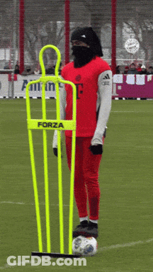 A Person Wearing A Red Jersey With The Letter F On It Stands Next To A Yellow Forza Mannequin GIF