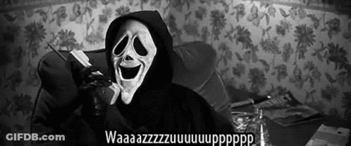 A Person Wearing A Scream Mask Is Talking On A Cell Phone While Sitting On A Couch . GIF