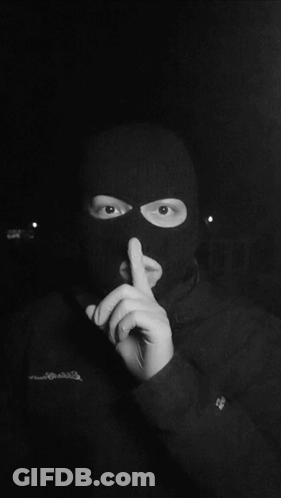 A Person Wearing A Ski Mask Has Their Finger To Their Mouth GIF