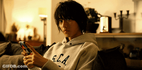 A Person Wearing A Sweatshirt That Says G.c.a. Looks At Their Phone GIF