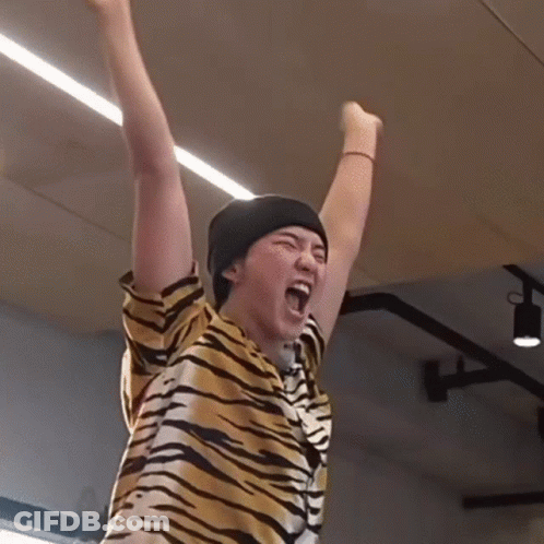 A Person Wearing A Tiger Print Shirt And A Black Beanie Is Raising Their Arms In The Air GIF