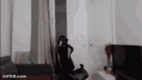 A Person Wearing A Virtual Reality Headset Is Sitting In A Living Room . GIF