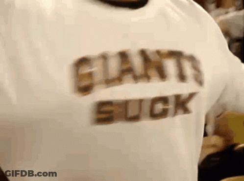 A Person Wearing A White Shirt That Says Giants Suck On It . GIF