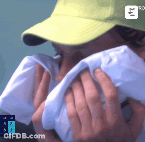 A Person Wearing A Yellow Hat Covering Their Face With A Towel GIF