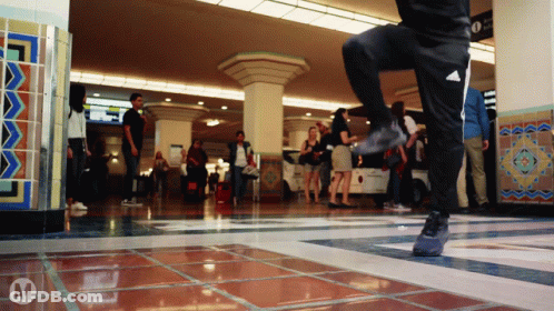 A Person Wearing Black Adidas Pants Is Dancing In A Crowded Room GIF
