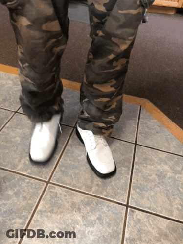 A Person Wearing Camo Pants And White Shoes Stands On A Tiled Floor GIF