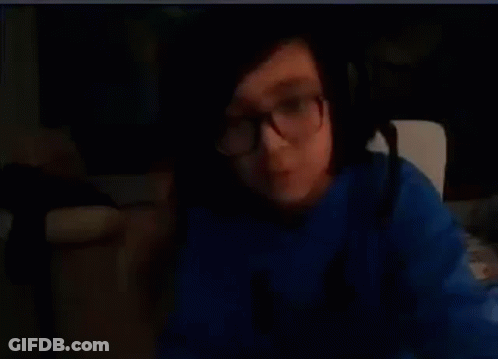 A Person Wearing Glasses And A Blue Shirt Is Making A Funny Face . GIF