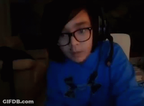 A Person Wearing Glasses And A Blue Sweater Is Sitting In A Chair . GIF