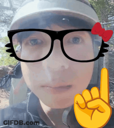 A Person Wearing Glasses And A Hat With A Red Bow On Them GIF