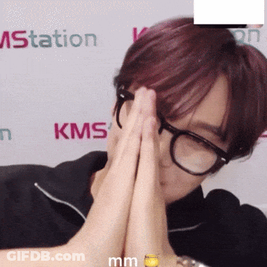 A Person Wearing Glasses Is Covering Their Face In Front Of A Kms Sign GIF