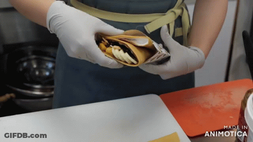 A Person Wearing Gloves Is Holding A Food Item That Says Made In Animatica GIF