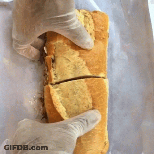 A Person Wearing Gloves Is Holding A Sandwich That Has Been Cut In Half GIF