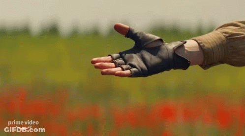 A Person Wearing Gloves Reaches Out To Another Person 'S Hand With A Prime Video Logo In The Background GIF
