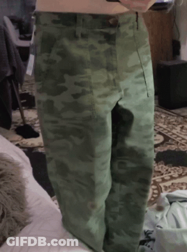 A Person Wearing Green Camo Pants Is Standing On A Rug GIF