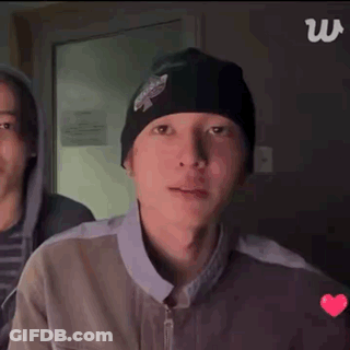 A Person Wearing Headphones And A Beanie Is Clapping Their Hands . GIF