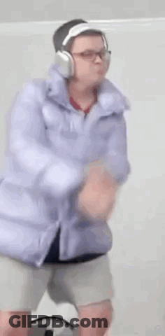 A Person Wearing Headphones And A Purple Jacket Is Dancing . GIF