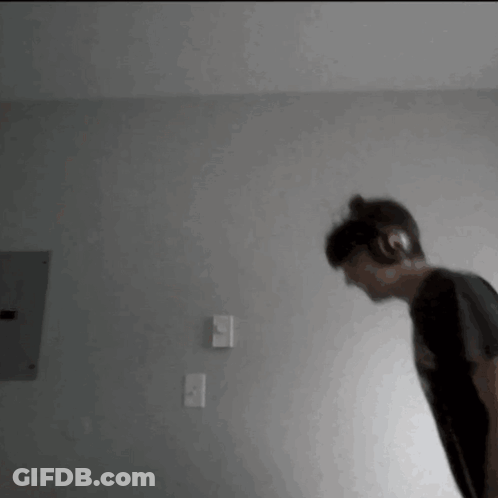 A Person Wearing Headphones Is Standing In A Room . GIF