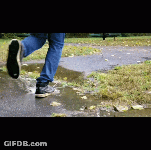 A Person Wearing Nike Shoes Runs Through A Puddle Of Water GIF