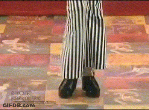 A Person Wearing Striped Pants And Black Shoes Is Standing On A Checkered Floor .. GIF