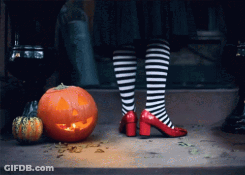 A Person Wearing Striped Socks And Red Heels Standing Next To A Carved Pumpkin GIF
