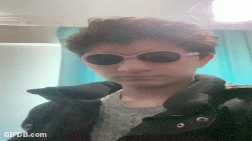 A Person Wearing Sunglasses And A Black Jacket Looks Down GIF